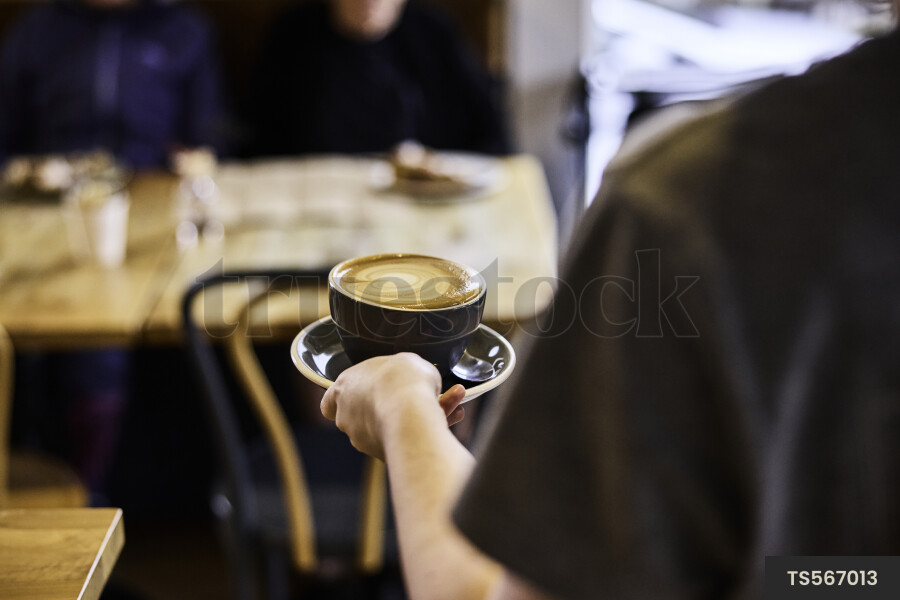 Waiter carrying coffee to customers in cafe