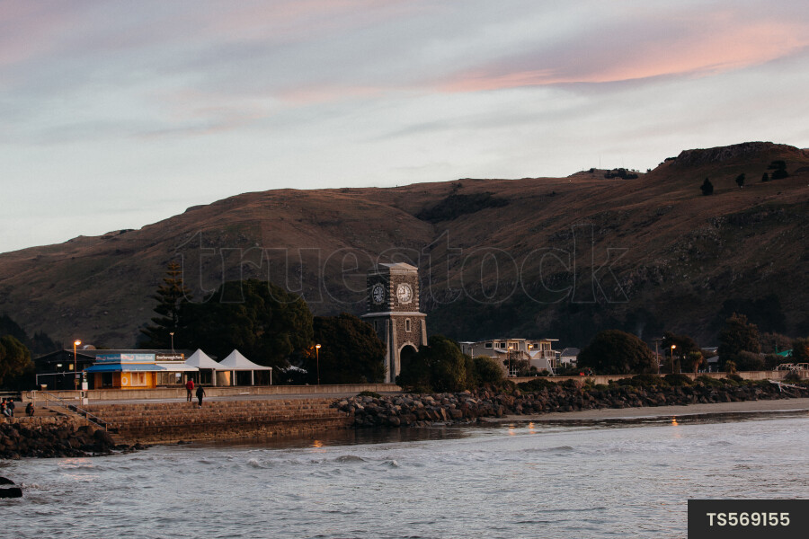 Clock tower by sea at sunset
