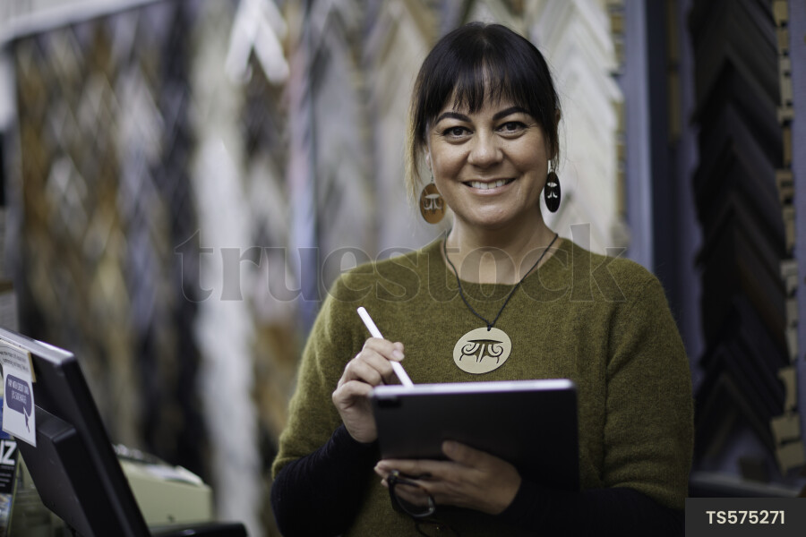 Woman working with tablet PC in picture frame store