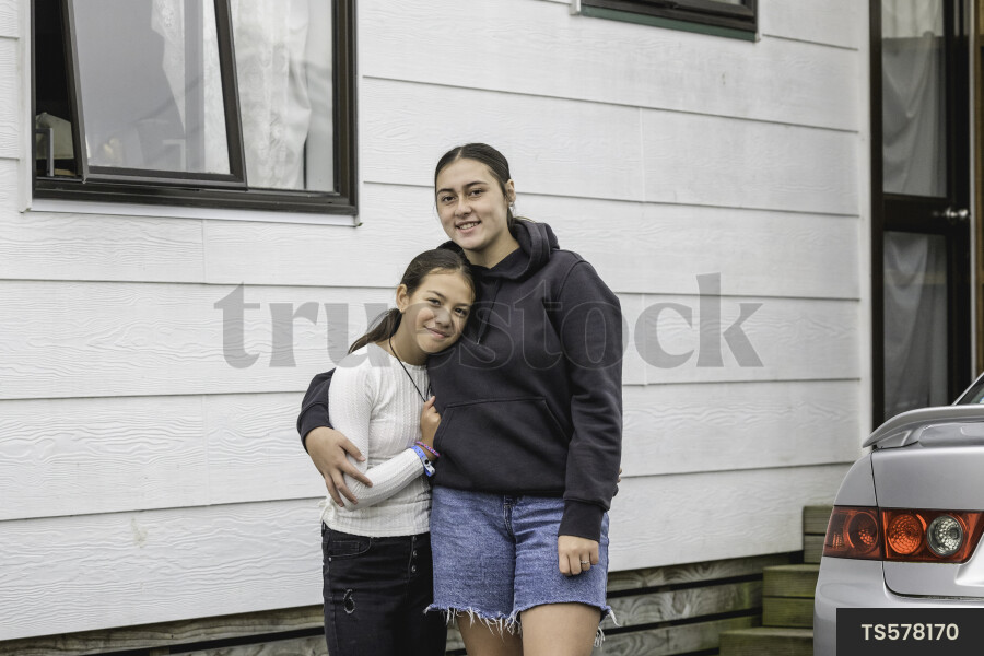 Portrait of sisters by house