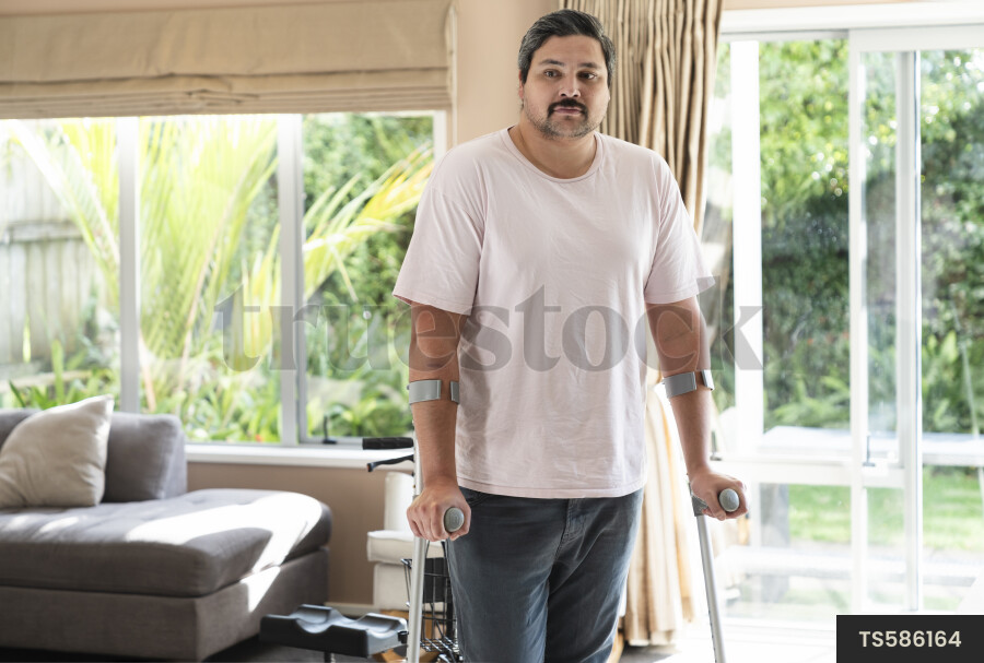 Disabled man with crutches in house