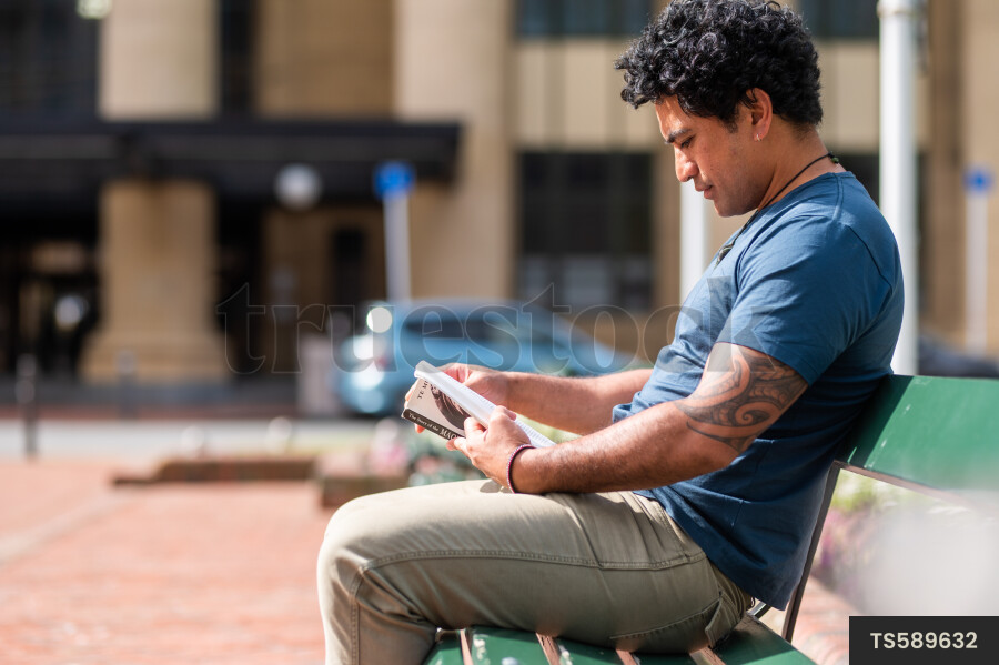 Man Reading Book on Bench