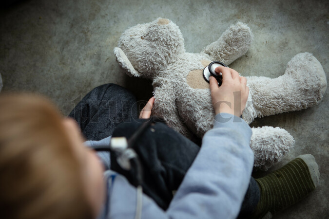 Child playing pretend Doctors with teddy bear at home