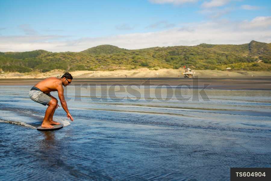 Man skim boarding on beach