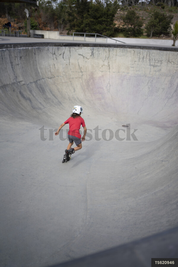 Back view of girl roller skating on skateboard ramp