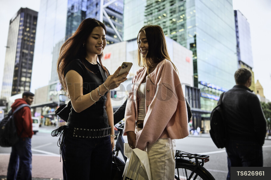 Happy friends with cell phone in street scene