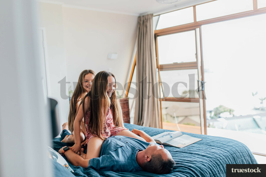 Dad and Daughters Playing on Bed