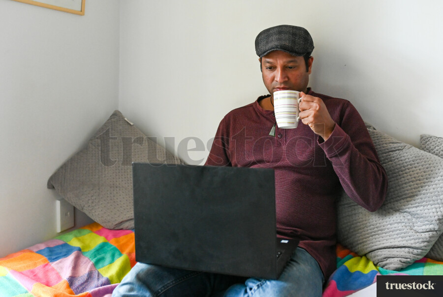 Adult male budgeting finances at home on the bed