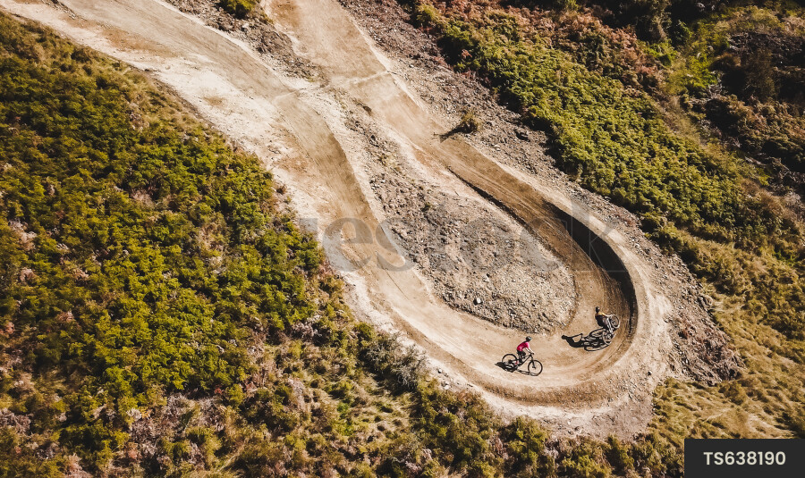 People mountain biking on dirt trail in mountain