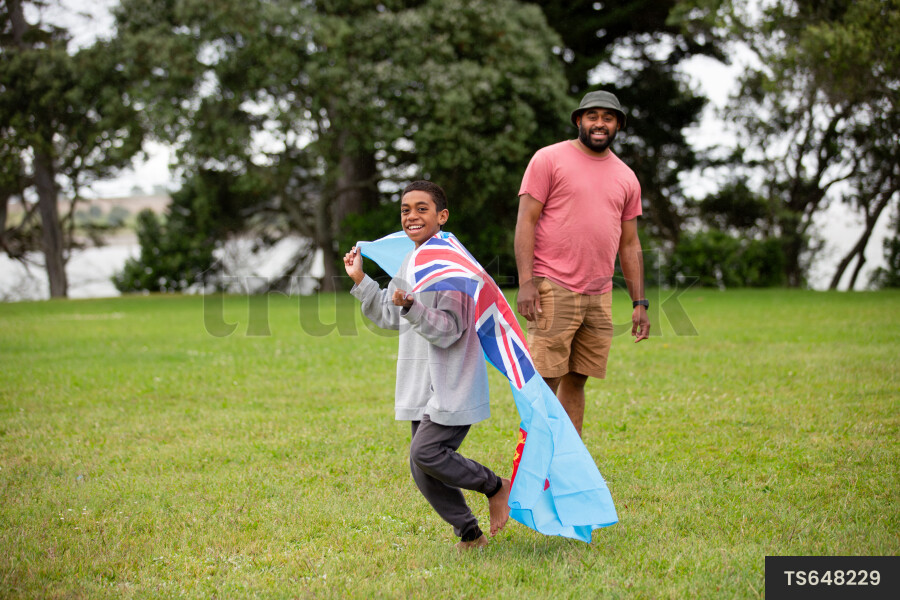 Boy with Fijian flag and his father in park