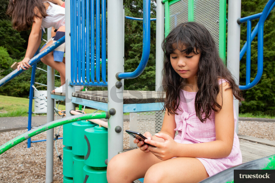 Child Looking at Phone, at Playground