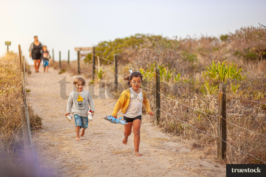 Children running down sand walkway at the beach