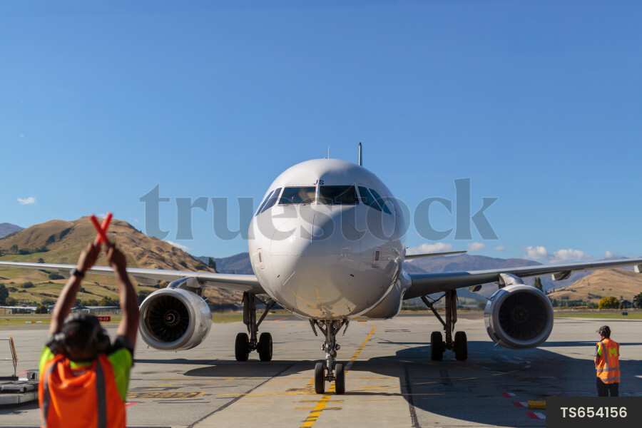 Worker directing airplane on runway
