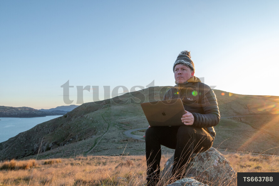 Man with laptop on rock