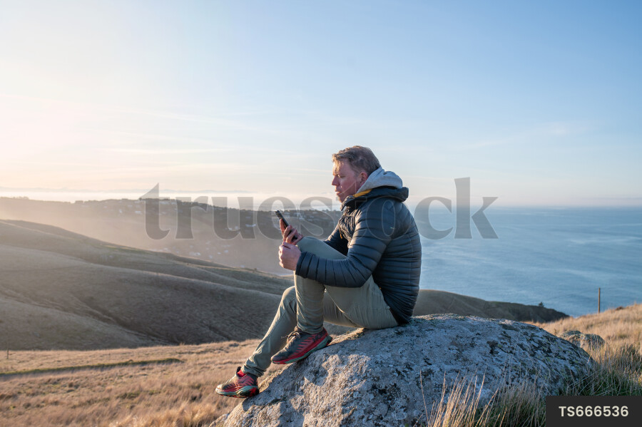 Man with smartphone on rock