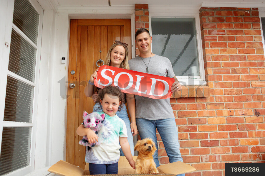 Family with sold sign by house