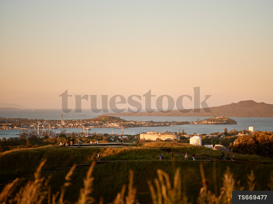 People walking on Mount Eden above Waitemata Harbour and Rangitoto