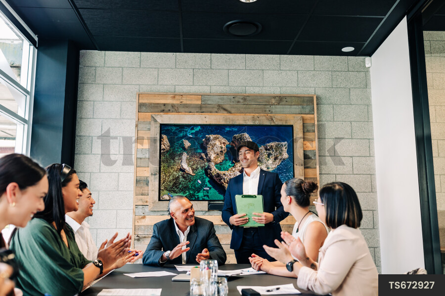 Businesspeople smiling and clapping during meeting in boardroom