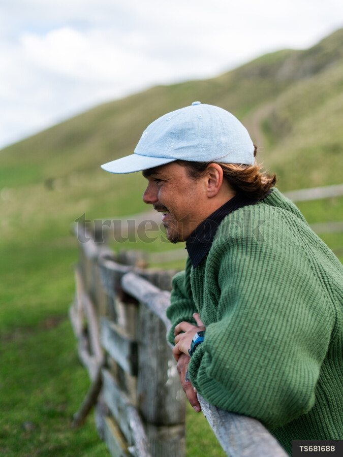 Young man leaning on fence