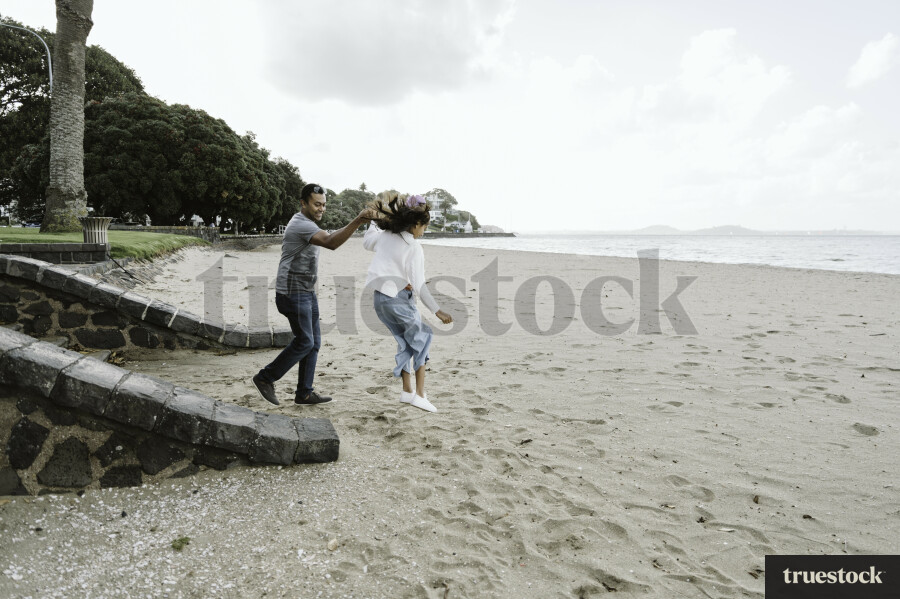 Dad Holding Daughters Hand on Beach