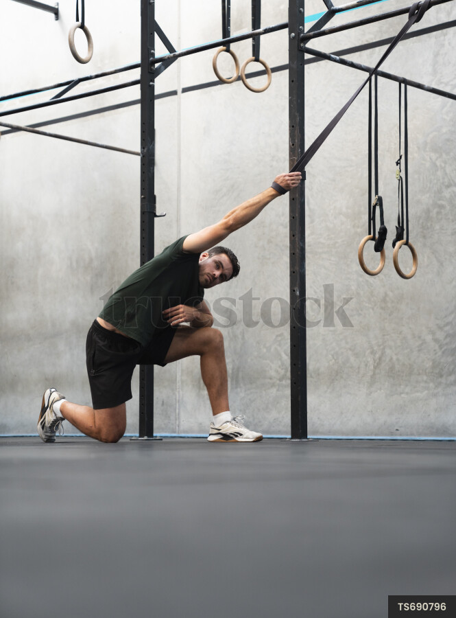 Young man stretching using exercise equipment in gym