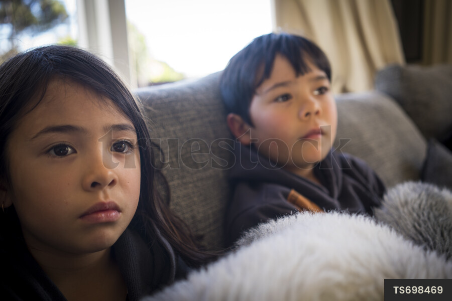 Brother and sister watching tv in living room