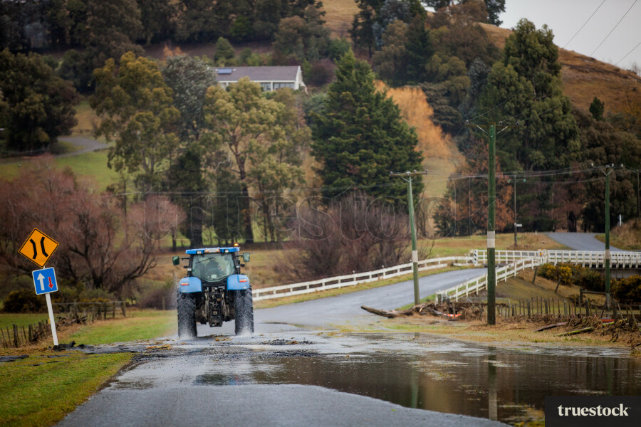 Tractor driving on the road after flooding and storm