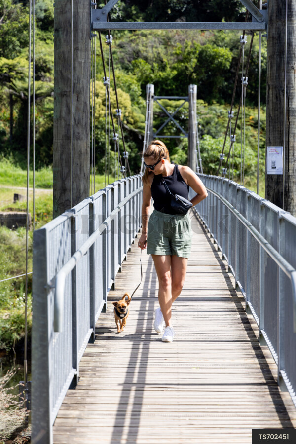 Woman walking dog on bridge