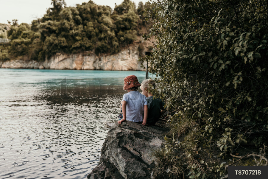 Boys sitting on rocks by sea