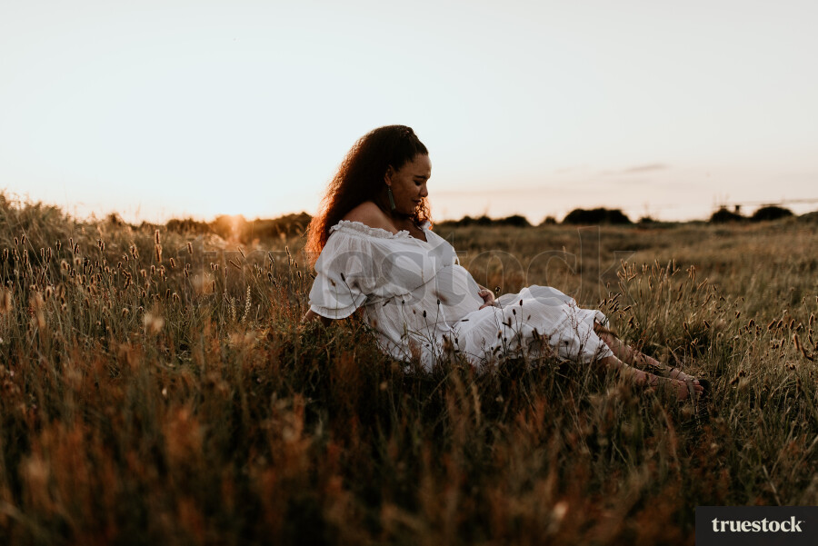 Woman Sitting in Field for Maternity Shoot