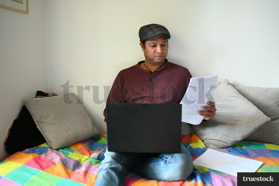 Adult male budgeting finances at home on the bed