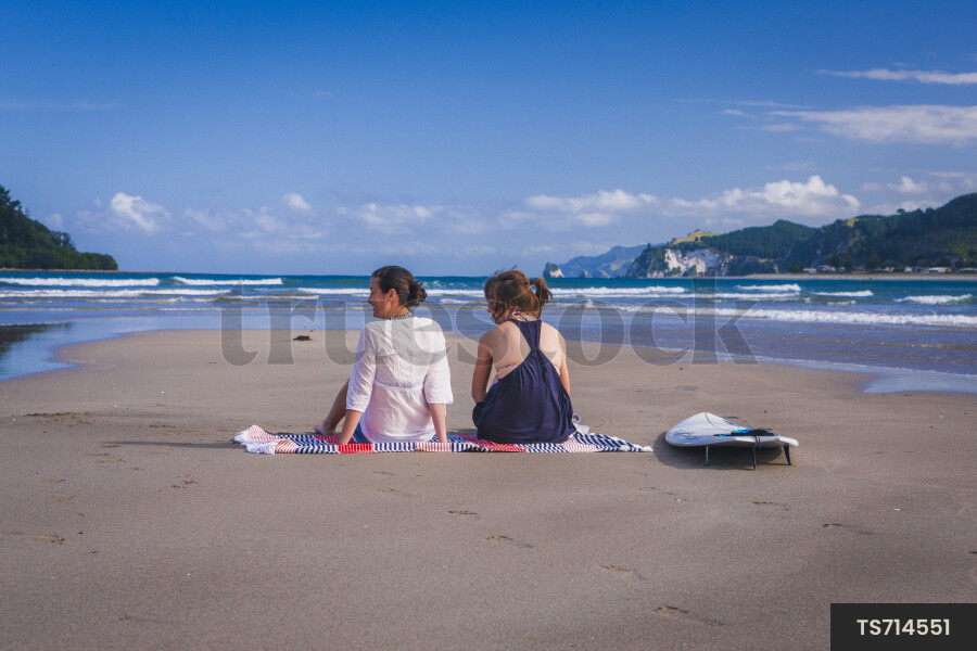 Women Sitting on Towel in Beach