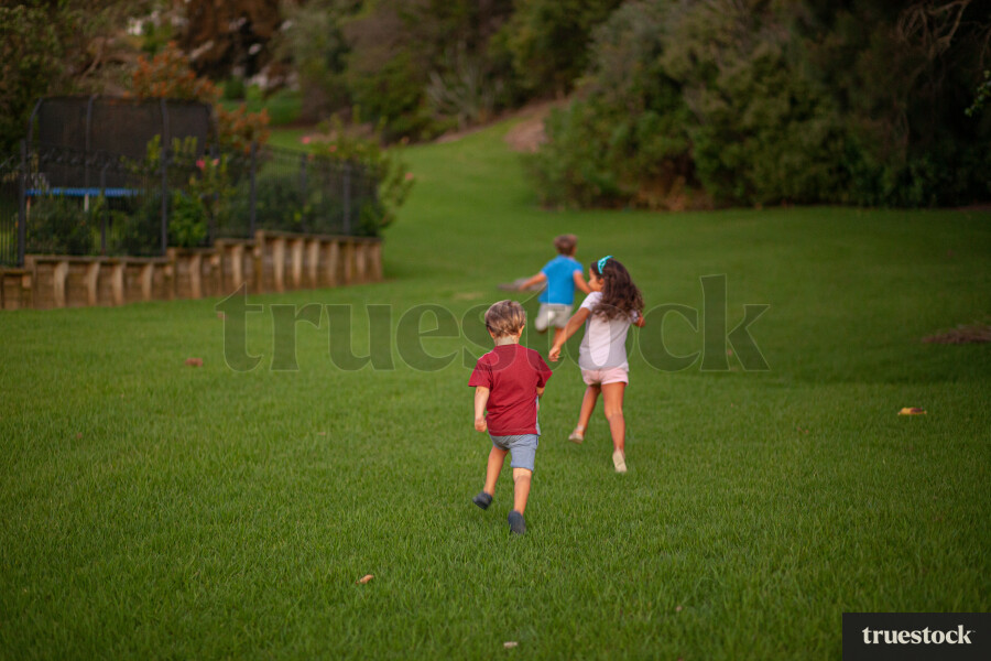 Children running down a grass hill