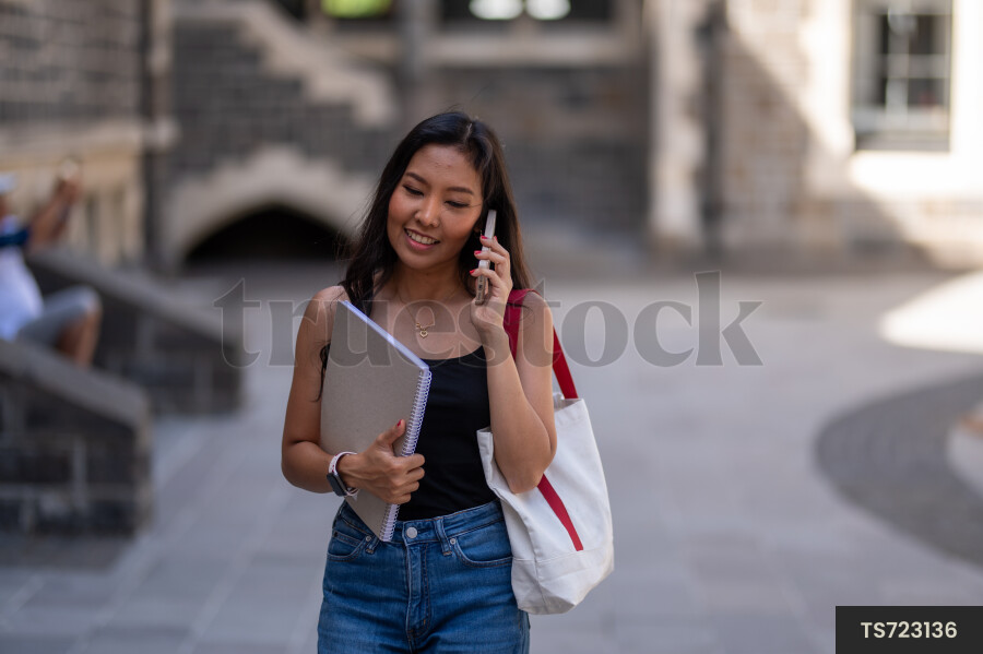 Smiling student with smartphone and book at university
