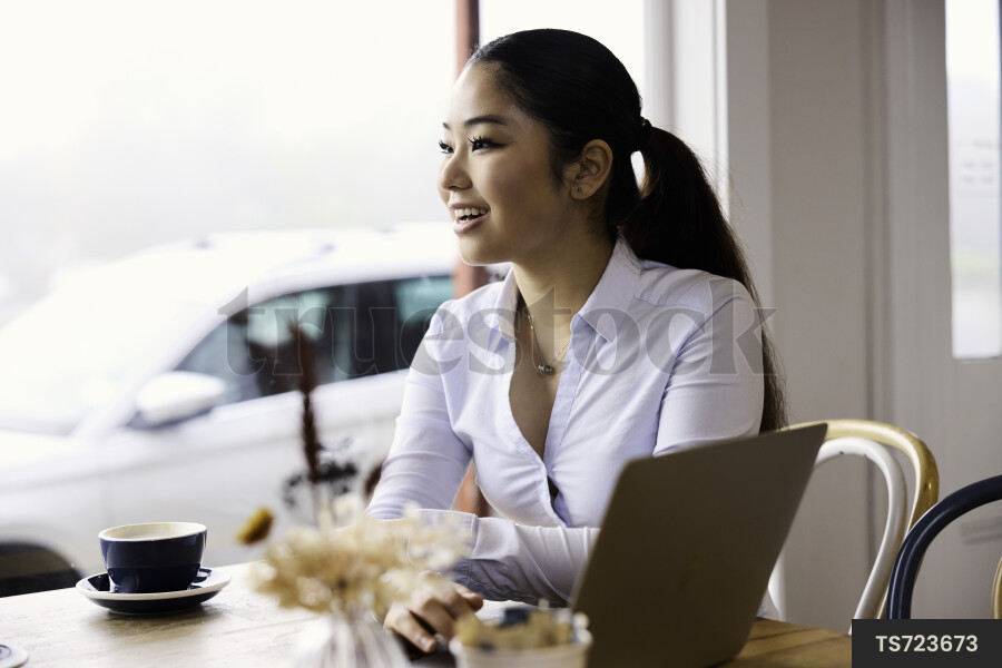Woman working remotely with technology in cafe