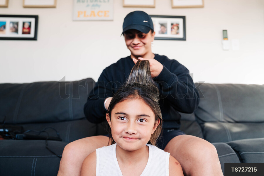 Mother and daughter with hand in hair on sofa in living room
