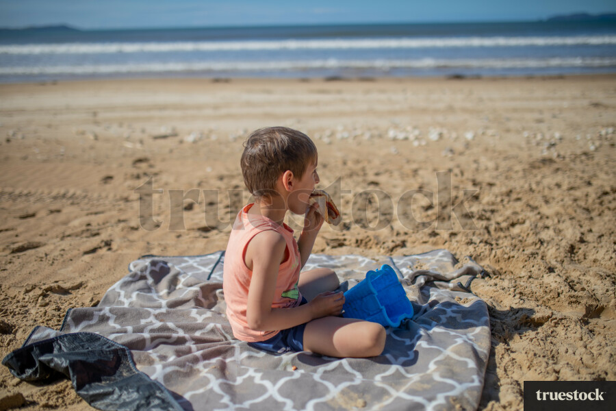 Young Boy eating Sausage at Beach