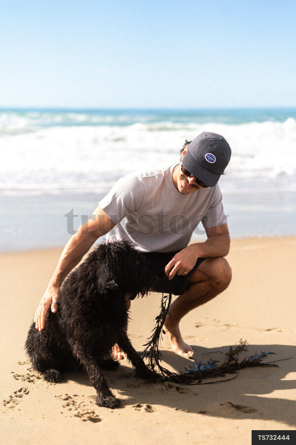 Man crouching by dog on beach during summer