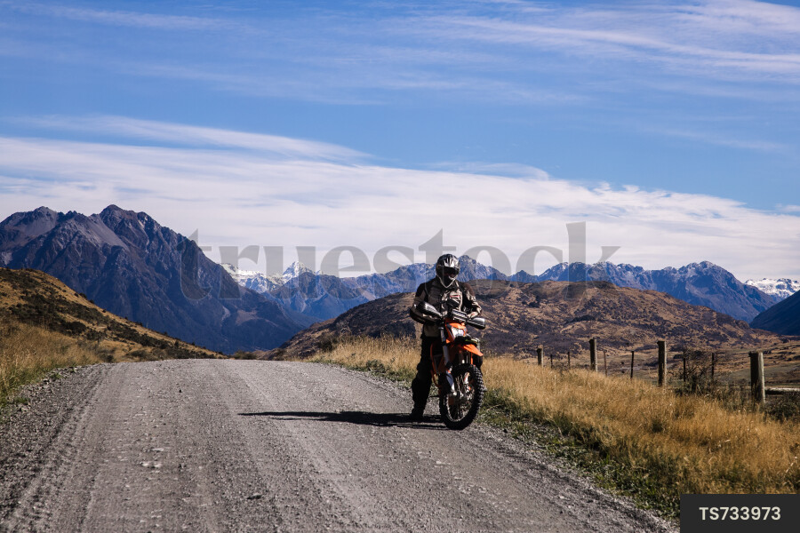 Man on motorcycle on dirt road in Southern Alps