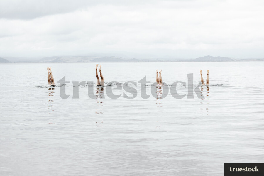 People doing handstands in the water at the beach