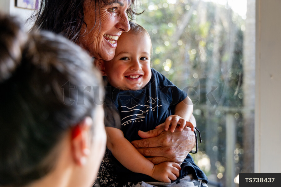 Happy mother and son with grandmother smiling in house