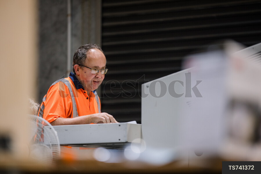 Man shredding paper at machine in recycling factory