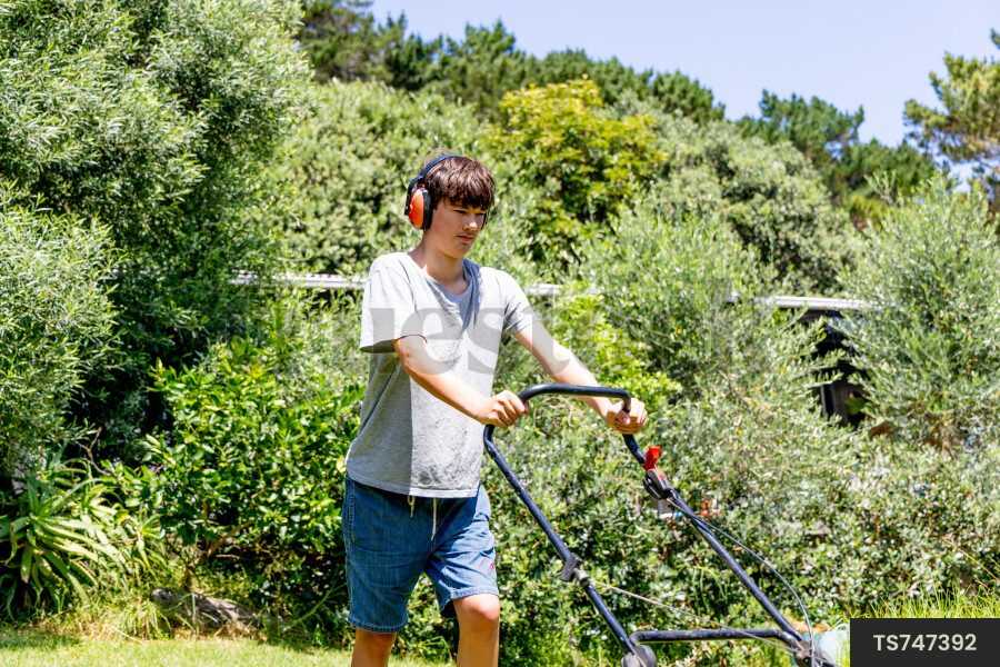 Teenage boy mowing lawn