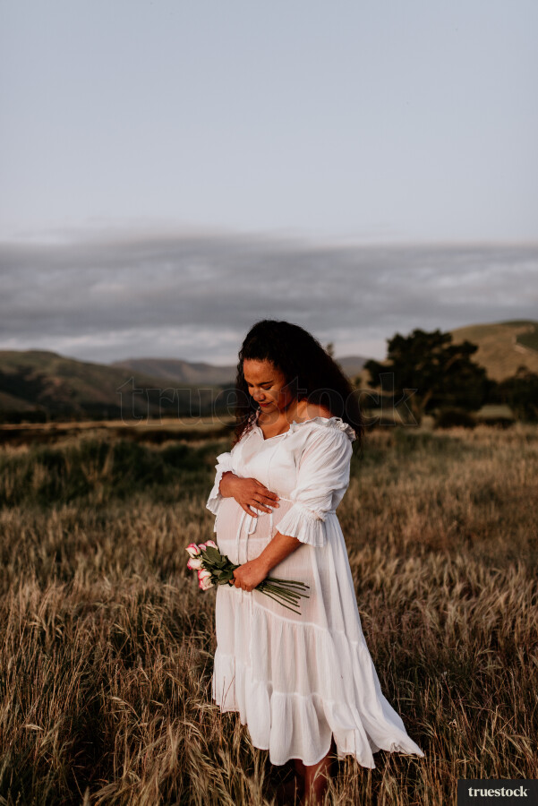 Woman Holding Flowers for Maternity Shoot