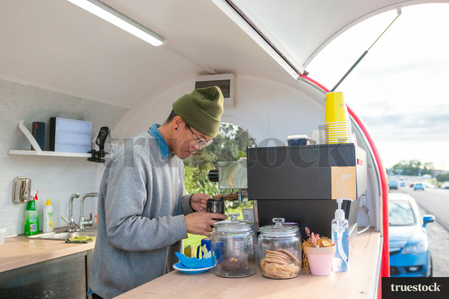 Barista making coffee orders for customers in a roadside coffee truck