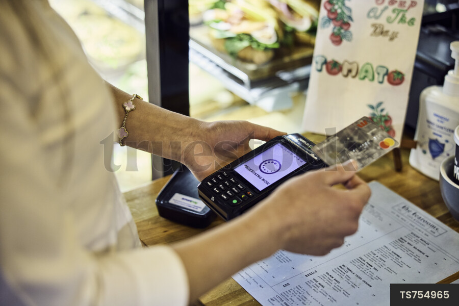 Close up of woman paying at counter in cafe