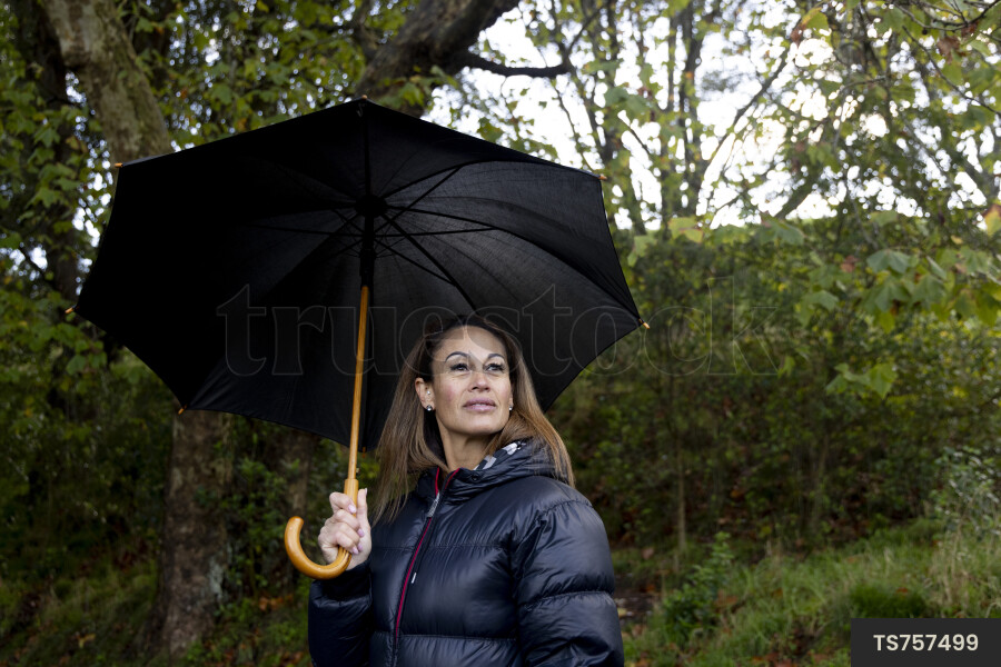 Woman in puffer jacket with umbrella in park