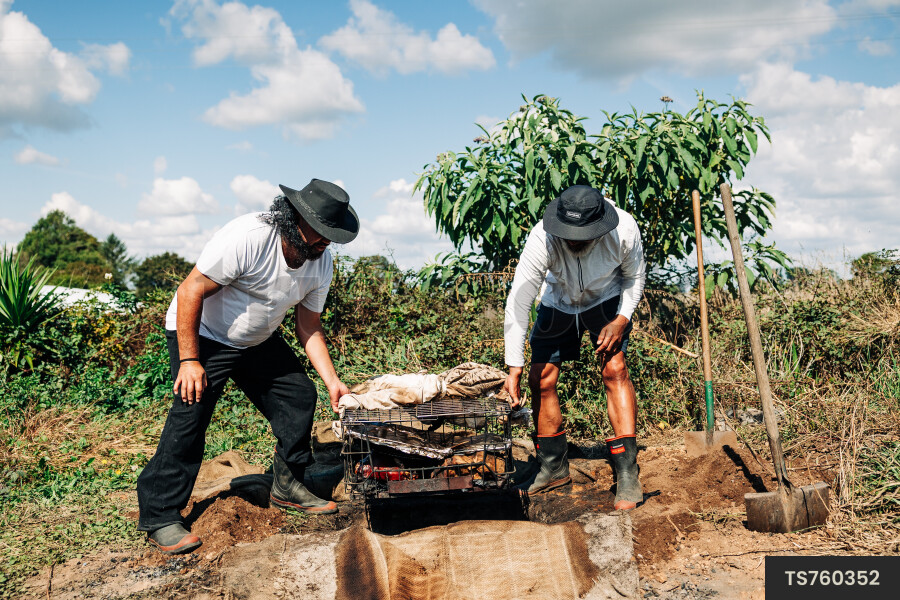 Father and son carrying grill basket in back yard