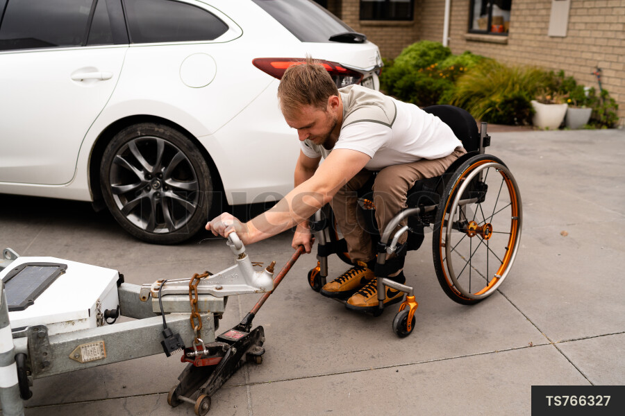 Man in wheelchair using trailer jack