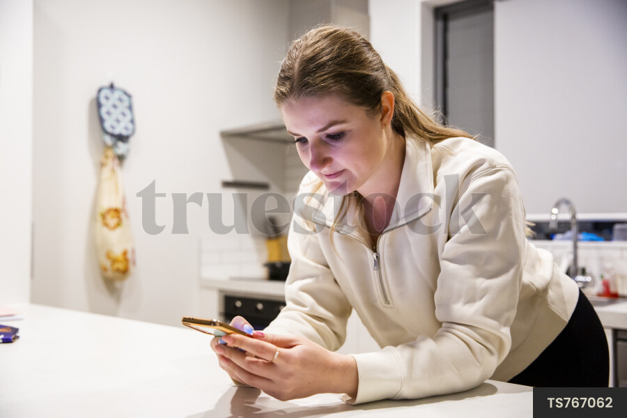 Woman Using Phone in Kitchen
